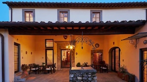 A courtyard with a stone fountain, outdoor seating, and a covered area with a tiled roof.