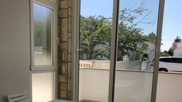 A room with a white table and chairs, large windows, and a view of the outside. - Cozy apartment on the ground floor with a small terrace (Privlaka)