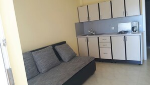 A compact living space with a sofa, kitchenette, and cabinets. - Cozy apartment on the ground floor with a small terrace (Privlaka)