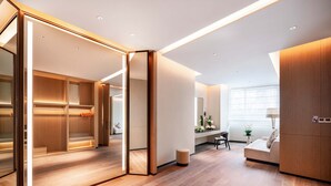 A modern hotel room with a wooden floor, a glass partition, a sofa, a small table, and a lamp. - MUMIAN Cheng'du Dong'an Lake, Unbound Collection (Chengdu)