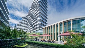 A modern hotel with a curved facade, outdoor seating area, and a water feature. - MUMIAN Cheng'du Dong'an Lake, Unbound Collection (Chengdu)