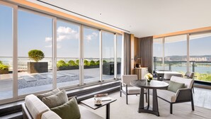 A modern hotel room with large windows, a sofa, a table, and a chair. - MUMIAN Cheng'du Dong'an Lake, Unbound Collection (Chengdu)