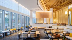 A modern hotel lobby with large windows, a central seating area, and a wooden ceiling design. - MUMIAN Cheng'du Dong'an Lake, Unbound Collection (Chengdu)