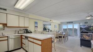 Une cuisine spacieuse dotée d’un îlot central, un coin repas avec vue et un salon équipé d’une grande télévision.