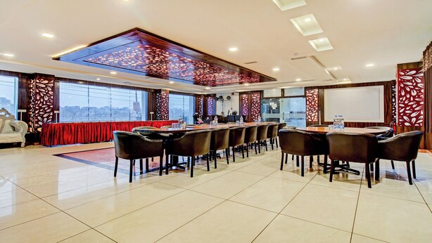 Un salón de conferencias con una larga mesa, sillas y un mantel rojo.