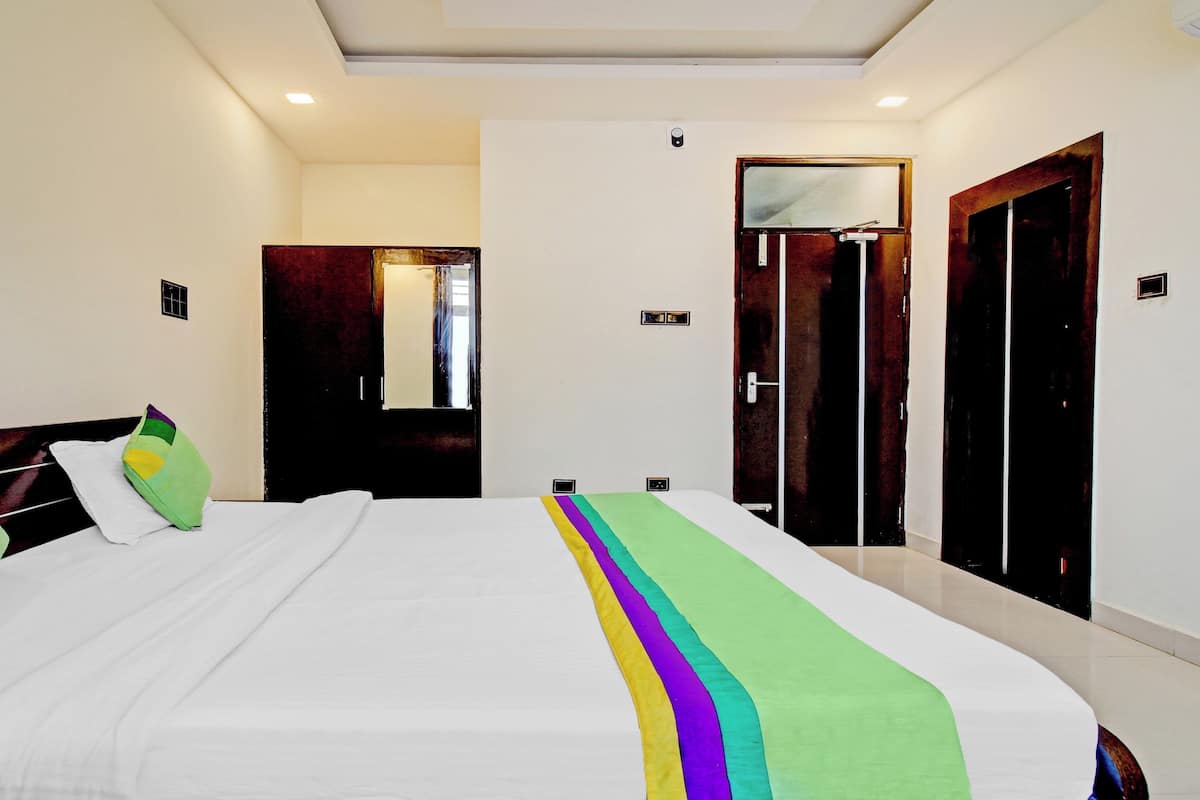 A hotel room with a large bed, a wardrobe, and a door.