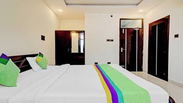 A hotel room with a large bed, a wardrobe, and a door.
