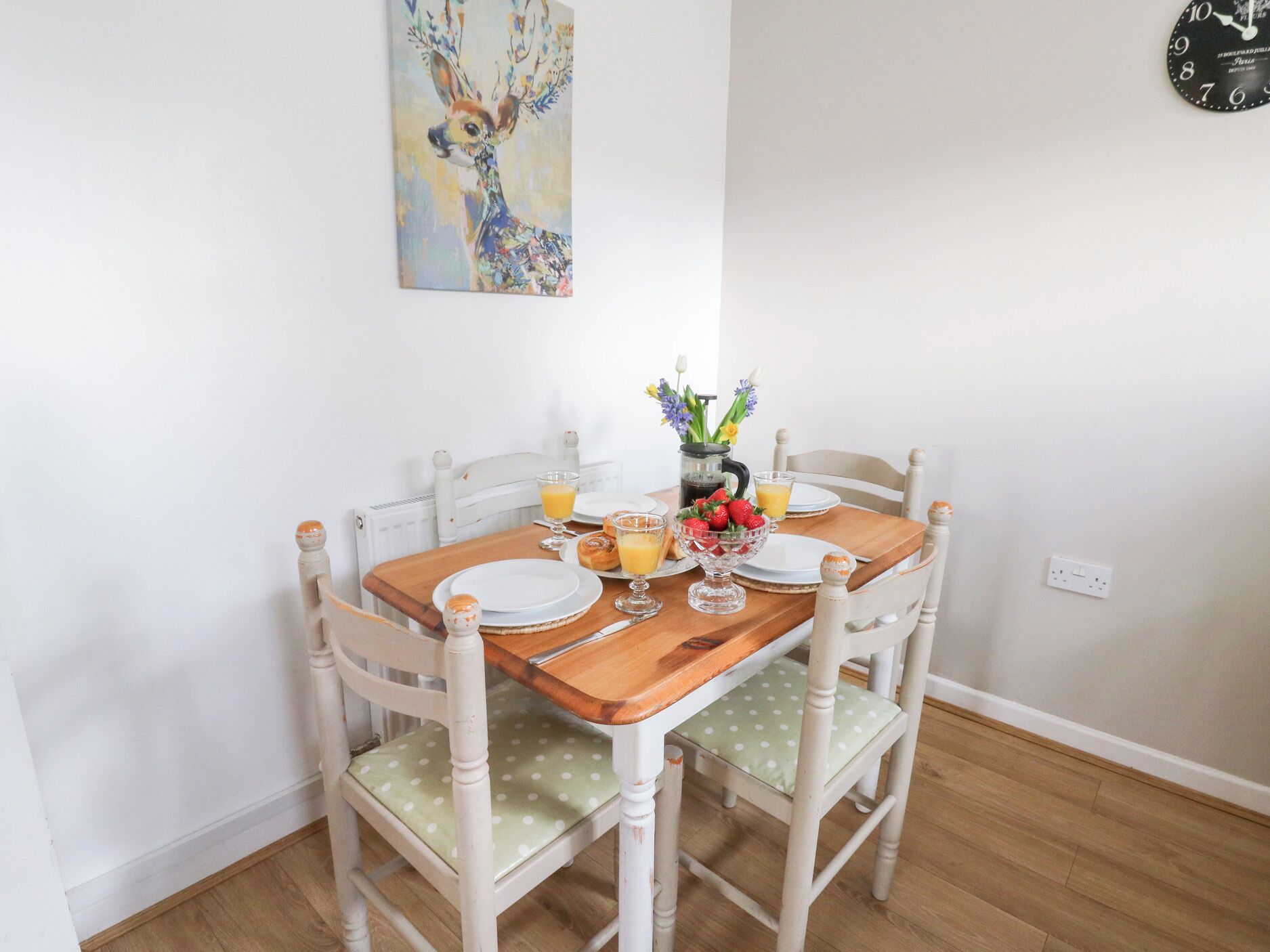 Una mesa de comedor con un centro de mesa floral, platos, vasos y un reloj en la pared.
