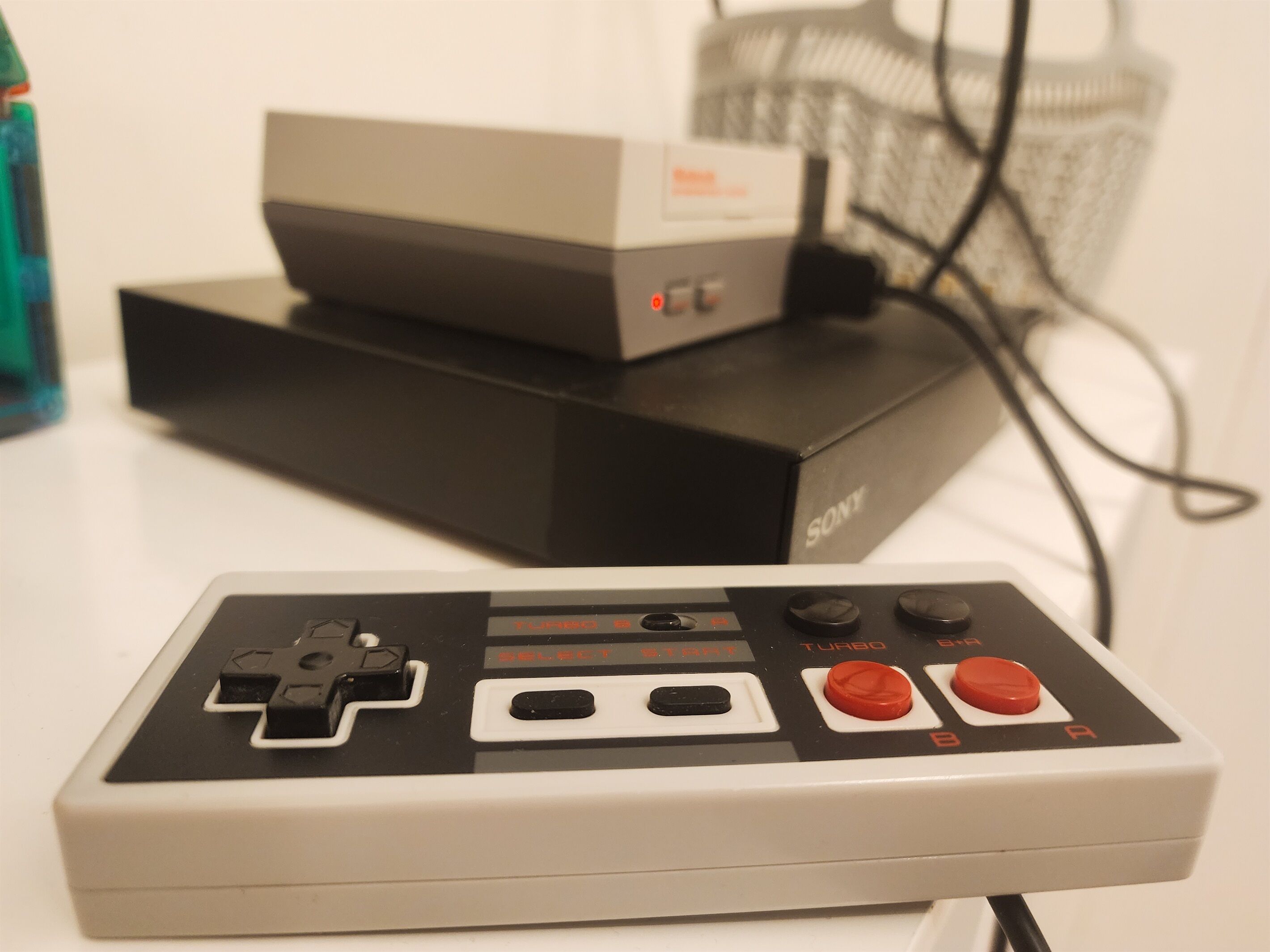 A Sony gaming console with a controller, a power strip, and a cable.