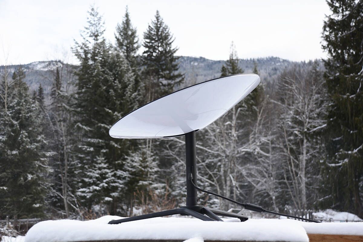 A satellite dish mounted on a stand with a snowy landscape in the background.