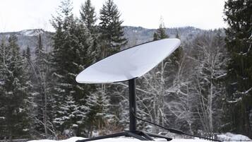 A satellite dish mounted on a stand with a snowy landscape in the background.