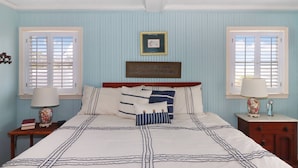 A bedroom with a bed, two nightstands, a framed quote on the wall, and two windows with shutters. - An Unfettered View | Wheelchair Accessible Oyster Bay Waterfront Ranch w/ Long Pier for Crabbing (Chincoteague Island)