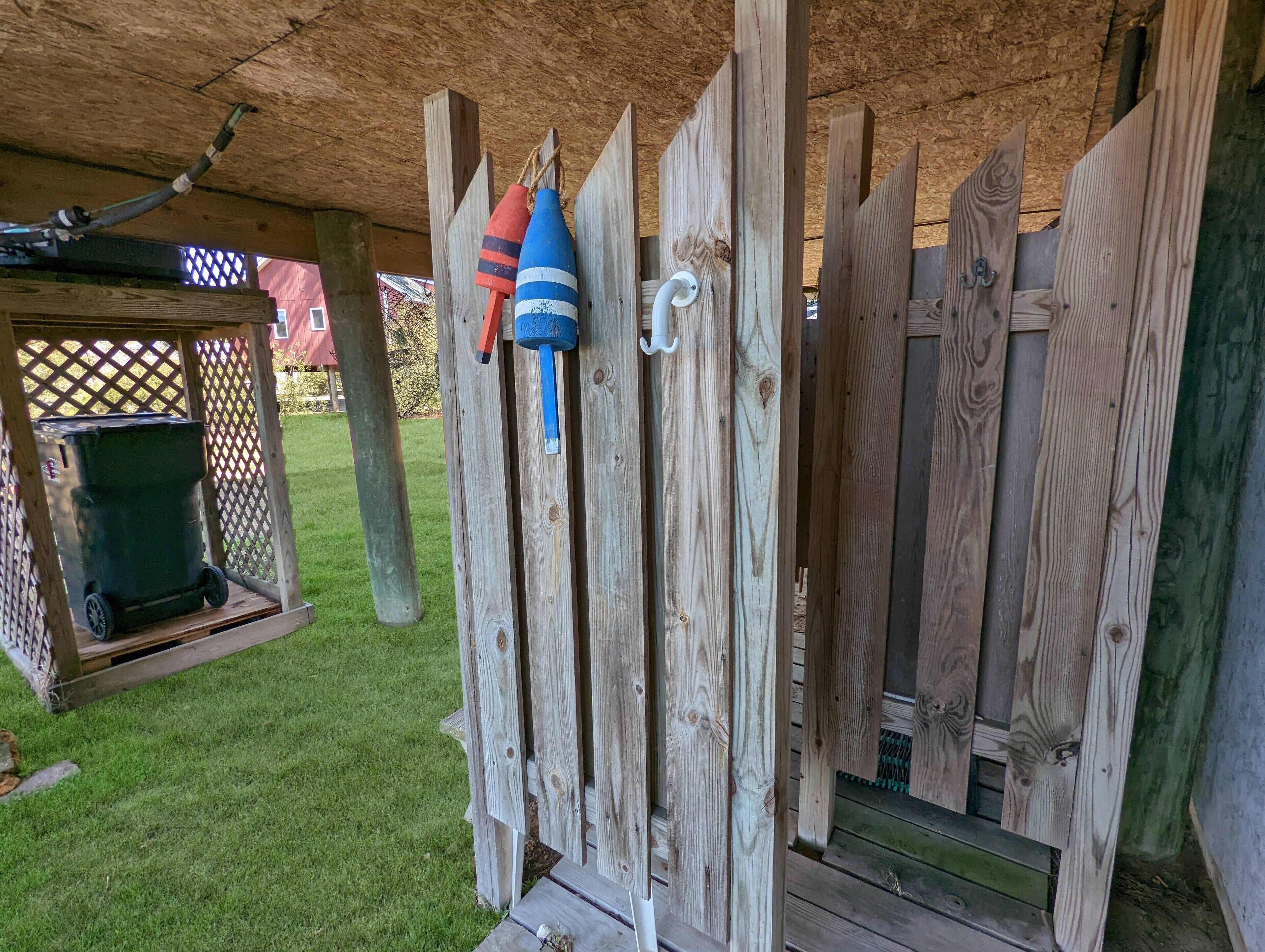 A wooden fence with a trash bin and a hose on the left.