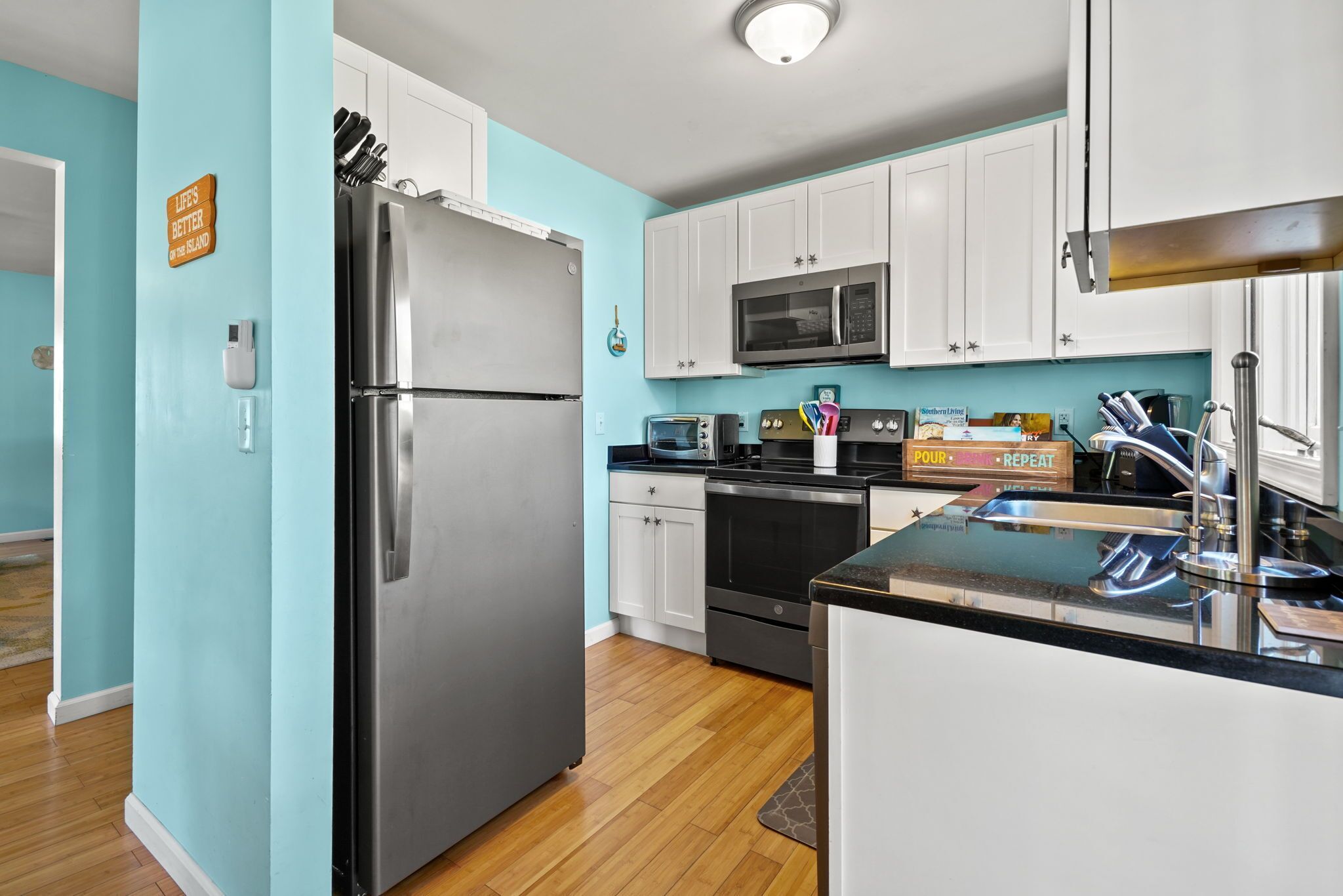 A modern kitchen with white cabinets, stainless steel appliances, and a blue accent wall.