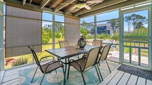 Veranda coperta con tavolo e sedie, ventilatore a soffitto e ampie finestre con vista sul paesaggio.