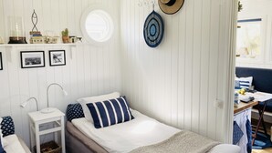 A bedroom with a bed, a bedside table, a lamp, a window, and a door leading to another room. - Beach cottage No. 7 SKREA STRAND (Hallands län)