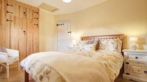 Un dormitorio con una cama grande, un armario de madera y una silla.