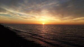 Un atardecer sobre un mar tranquilo con una playa en primer plano.