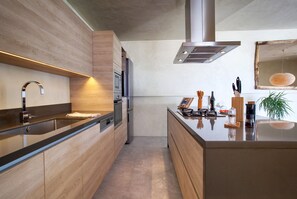 Cozinha moderna com armários de madeira, eletrodomésticos de aço inoxidável e uma ilha central com utensílios de bar.