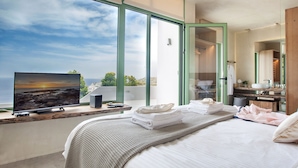 Una camera da letto moderna con un letto grande, una televisione e vista sul mare.
