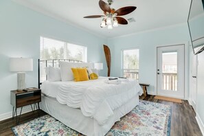 Une chambre à coucher avec un lit, un ventilateur de plafond, une fenêtre et une porte.