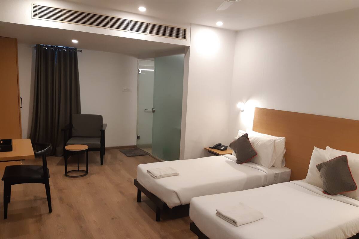 Ein Hotelzimmer mit zwei Betten, einem Schreibtisch, einem Stuhl und einem kleinen Tisch.