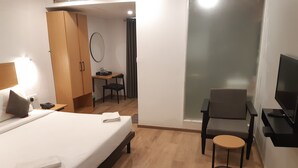 A hotel room with a bed, a desk, a chair, a TV, and a mirror.