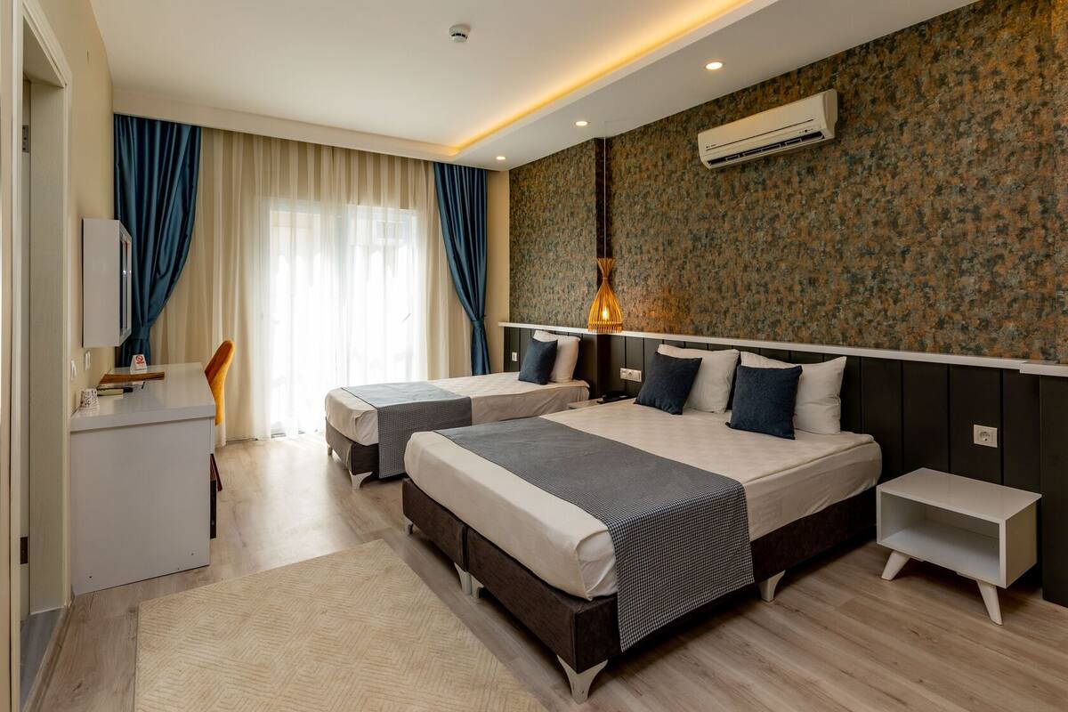A modern hotel room with two beds, a desk, and a wardrobe.
