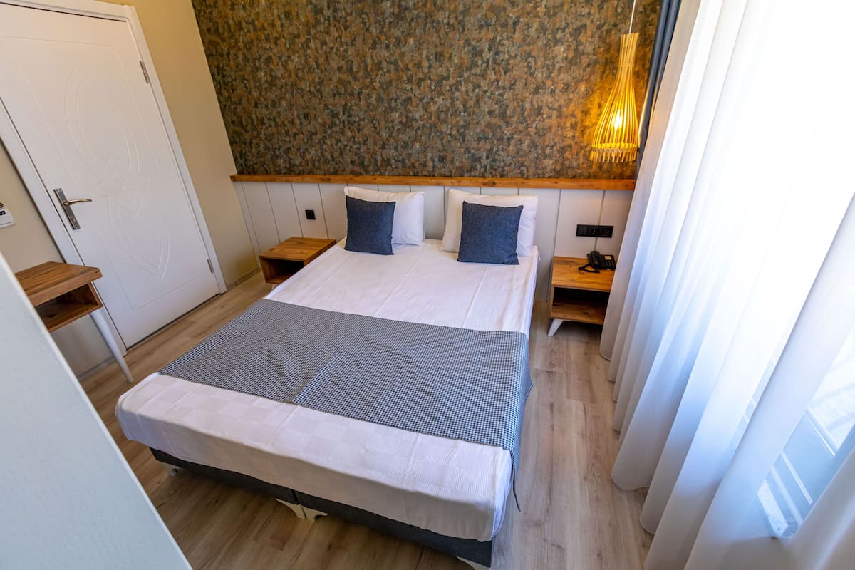 A neatly arranged bedroom with a bed, bedside tables, and a wall-mounted lamp.