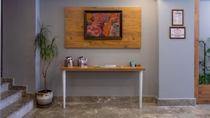Un'area reception con una scrivania in legno, un quadro incorniciato e una pianta in vaso.