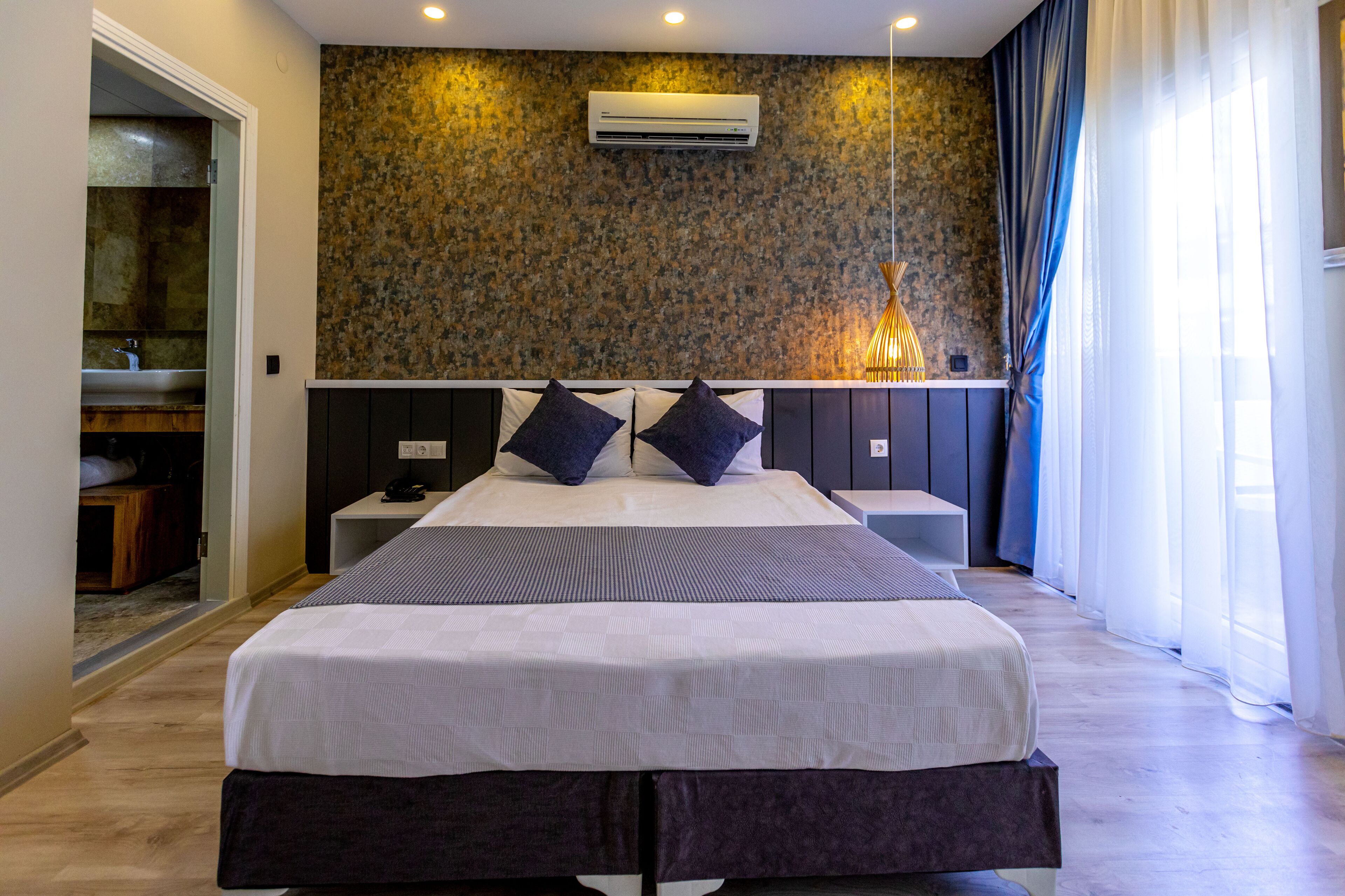 Un dormitorio moderno con una cama grande, un banco empotrado y un aire acondicionado de pared.