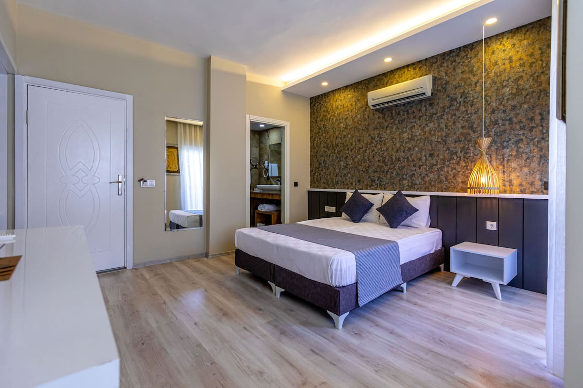 A modern bedroom with a large bed, bedside tables, a mirror, and a built-in wardrobe.