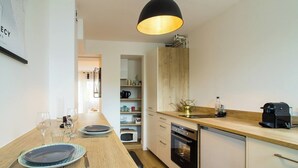 A modern kitchen with wooden countertops, a built-in oven, and a dining area with a table set for two.