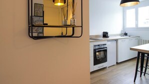 A modern kitchen with a built-in oven, a coffee machine, and a hanging pendant light.