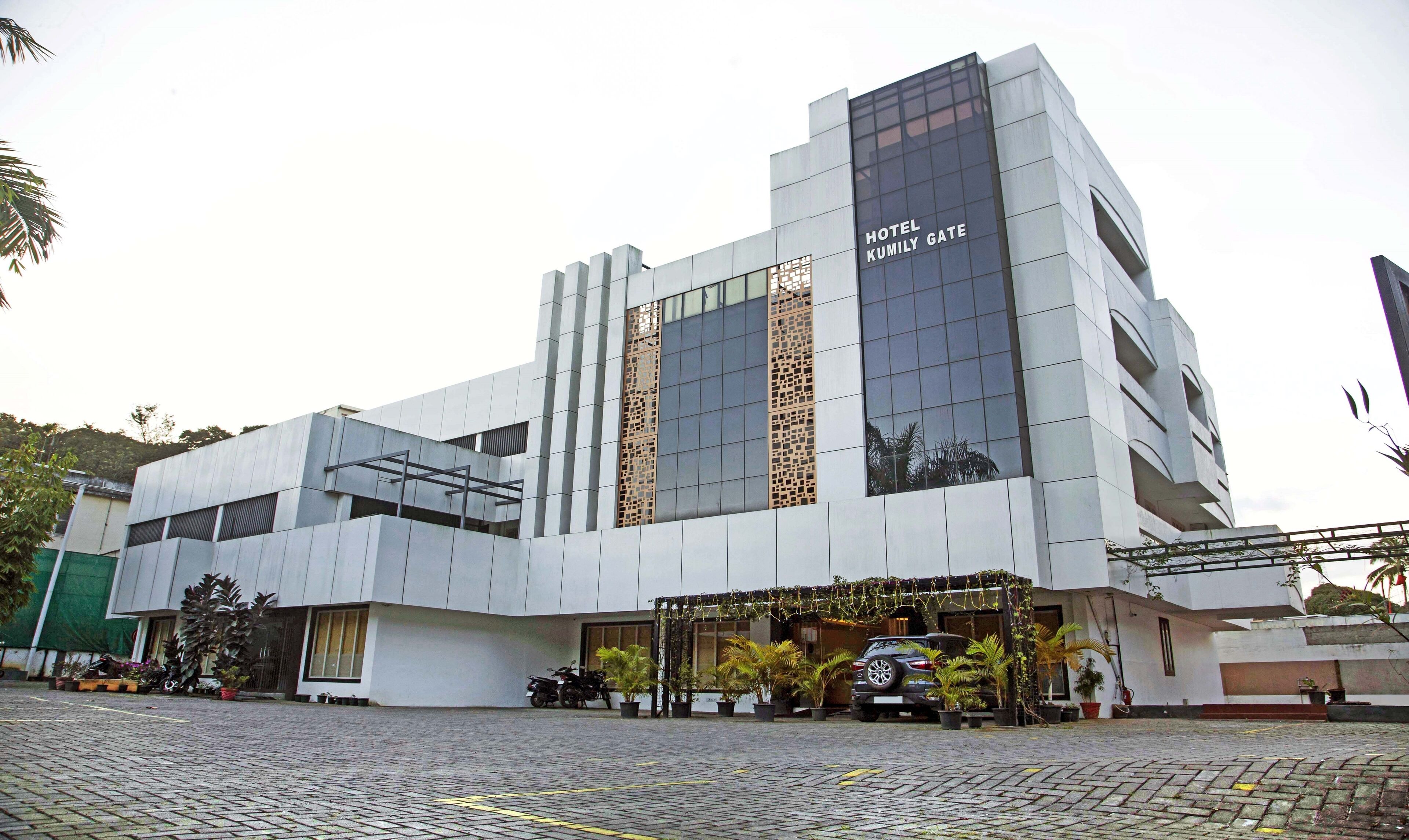 A modern hotel with a prominent entrance, large windows, and a sign reading "HOTEL KUMILY GATE".