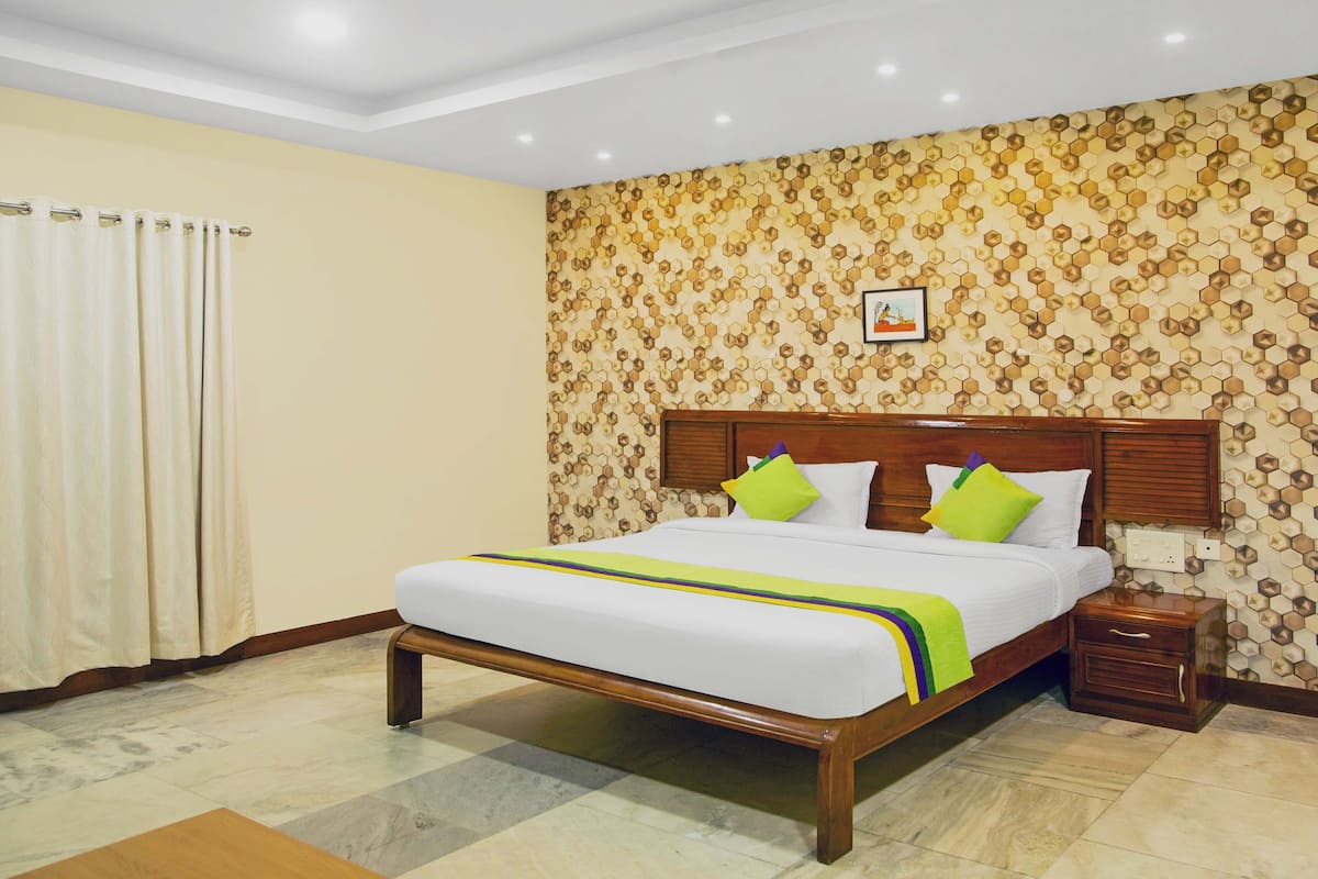 Una habitación de hotel con una cama grande, cabecero de madera y una pared con diseño.