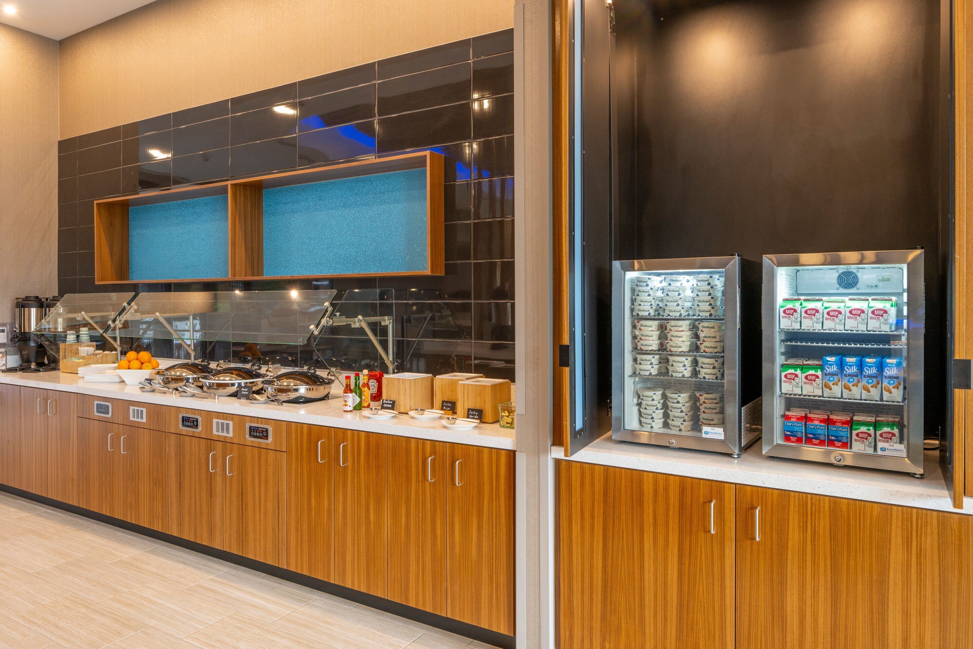 A modern kitchen with wooden cabinets, a stainless steel sink, and a beverage dispenser.