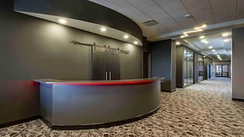Un'accogliente area reception moderna con una scrivania sagomata, un divisorio in vetro e un pavimento rivestito di moquette.