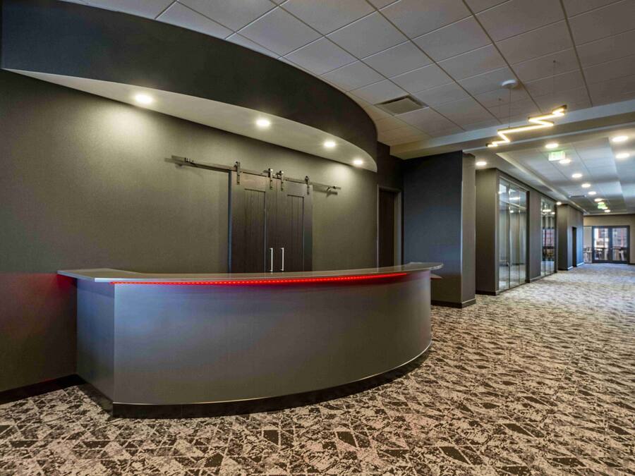 Un'accogliente area reception moderna con una scrivania sagomata, un divisorio in vetro e un pavimento rivestito di moquette.