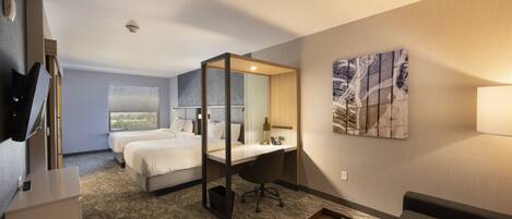 A hotel room with a large bed, a desk with a chair, a TV, and a window with a view.
