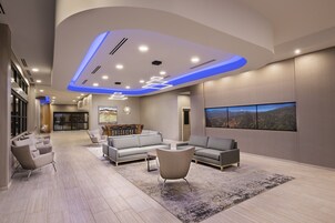 A modern living room with a sectional sofa, a coffee table, and a large window with a cityscape view.