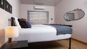 Een slaapkamer met een bed, bedlampje en een spiegel aan de muur.