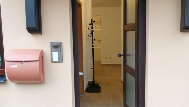 A doorway leading to a hallway with a coat rack and a mailbox on the wall. - Ground floor apartment with large balcony. Terrace near the forest, to feel good (Schöneck)