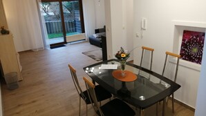 A dining area with a glass table, black chairs, and a vase with flowers. - Ground floor apartment with large balcony. Terrace near the forest, to feel good (Schöneck)