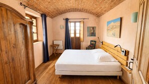 Ein Zimmer mit einem hölzernen Bett, einem kleinen Tisch, einem Stuhl und einer Heizung.