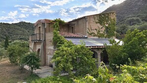 A rustic stone building with a tiled roof, surrounded by lush greenery and hills in the background. - L'Ombria – Charming Villa with a Private Pool (Belgodère)