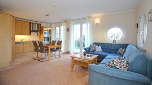 Ein modernes Wohnzimmer mit einem blauen Sofa, einem Couchtisch und einem Essbereich mit Stühlen und einem Tisch.