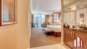 A hotel room with a large bed, a desk, a chair, and a view of the city. - MGM Signature-Jacuzzi F1 Track & Strip View Studio (Las Vegas)