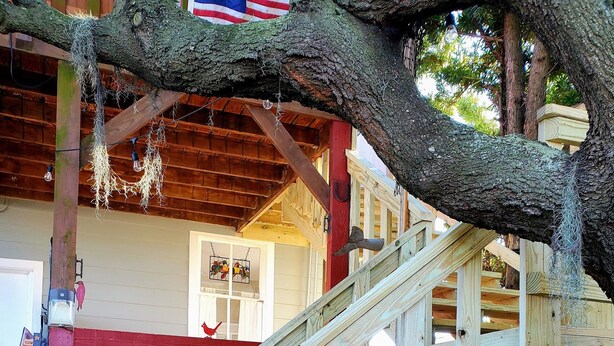 Un escalier en bois, avec une partie extérieure peinte en rouge, qui mène à une terrasse en bois.