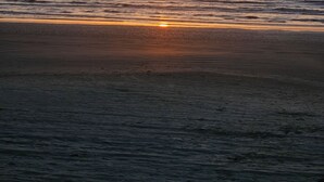 Une plage où le soleil se couche à l’horizon.